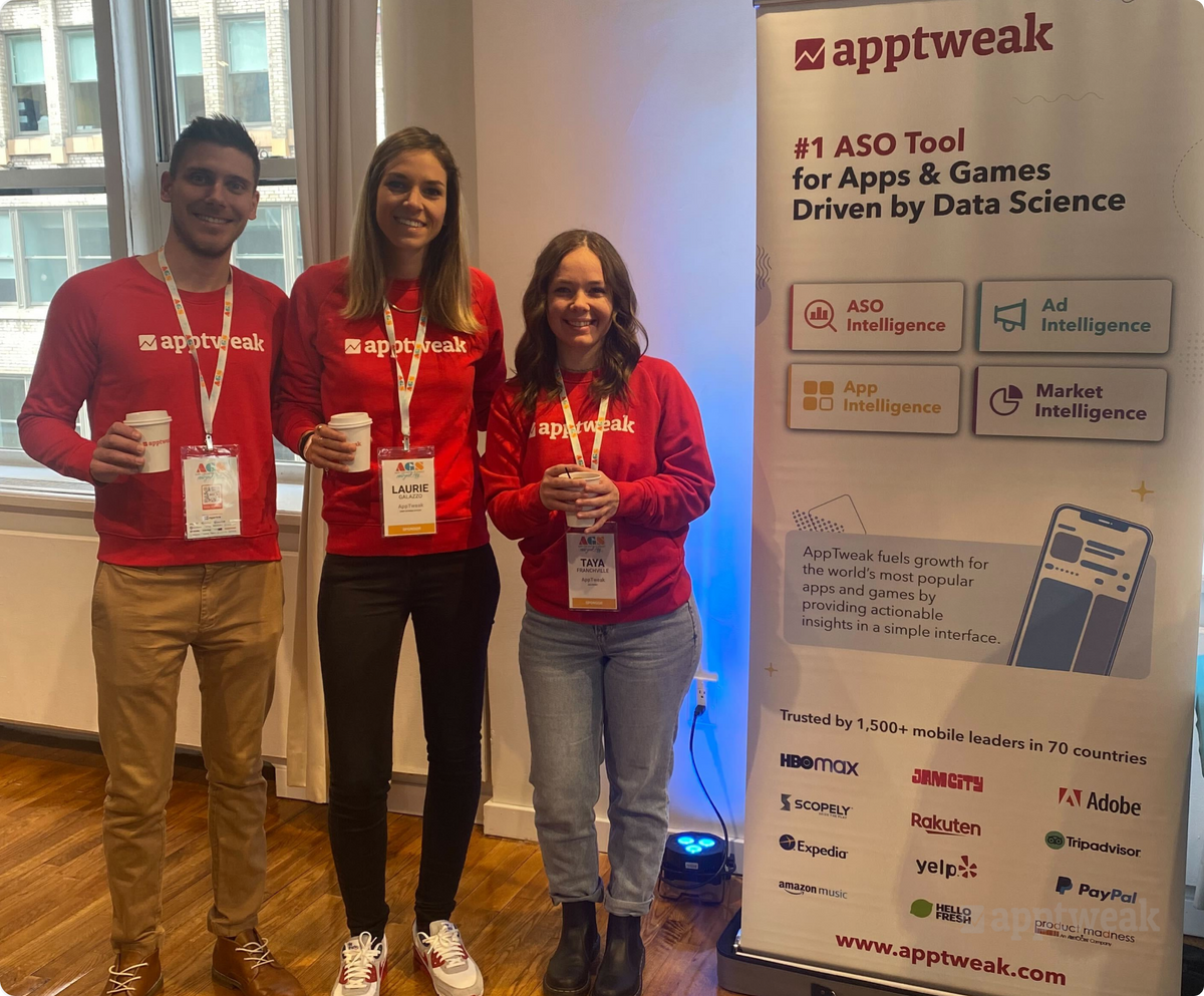 AppTweak 的三名员工与 AppTweak 横幅合影。